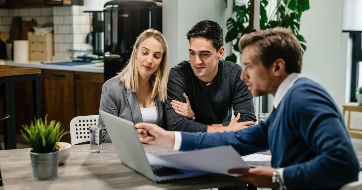 Jeune couple avec un agent immobilier devant un ordinateur