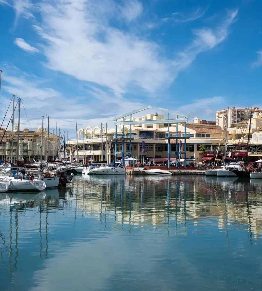 Port de plaisance de Benalmadena avec des bateaux amarrés et des bâtiments typiques sous un ciel bleu clair