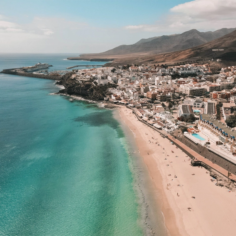 Village côtier de Fuerteventura avec des maisons blanches, des plages de sable et des montagnes en arrière-plan