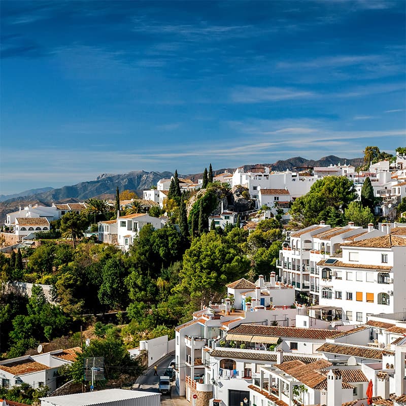 Vue pittoresque de Mijas avec ses maisons blanches traditionnelles entourées de verdure et montagnes en arrière-plan