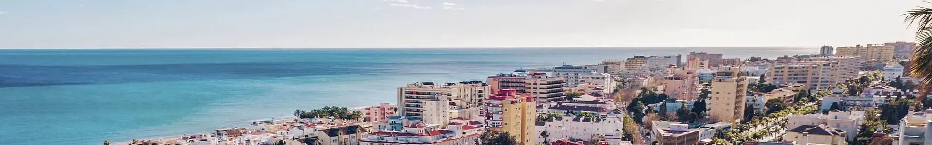 Vue panoramique sur la côte de Torremolinos, avec des bâtiments modernes bordant la mer Méditerranée sous un ciel bleu clair